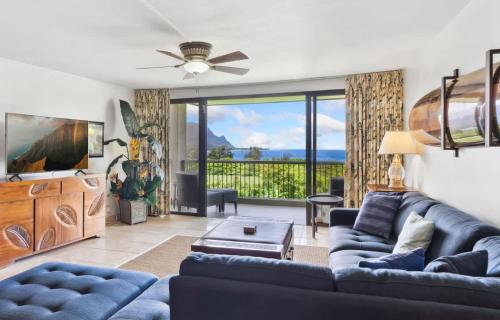 a living room with a blue couch and a large window at NEW Sunset Hideaway with Beach Access Pools & AC in Princeville