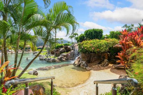 a water park with a waterfall and palm trees at NEW Sunset Hideaway with Beach Access Pools & AC in Princeville