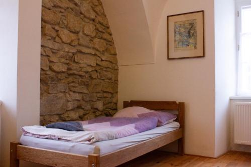 a bed in a room with a stone wall at Zámek Dobrohoř in Dobrohoř
