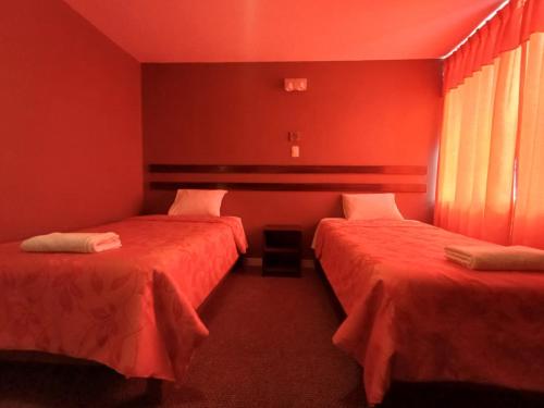two beds in a room with red walls at Colca Terra in Chivay