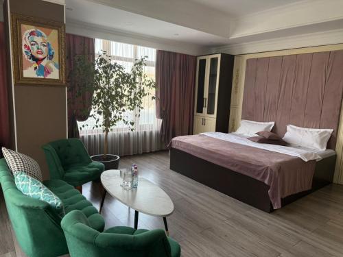 a hotel room with a bed and chairs and a table at Monroe Hotel in Almaty