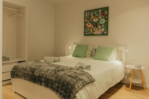 a bedroom with a large white bed with green pillows at Termas do Gerês Studio in Geres