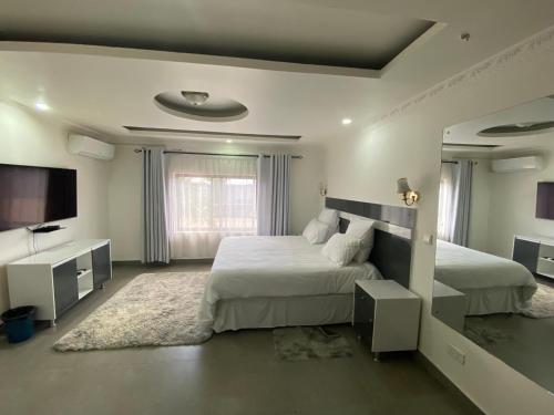 a bedroom with two beds and a flat screen tv at The 'C' Apartments in Mansa