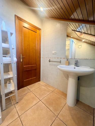 a bathroom with a sink and a wooden door at LS Alojamiento Turístico in Arcade