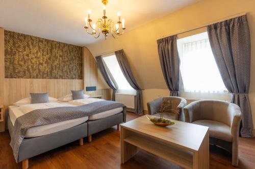 a bedroom with a bed and a chair and a table at Hotel Residence in Würzburg
