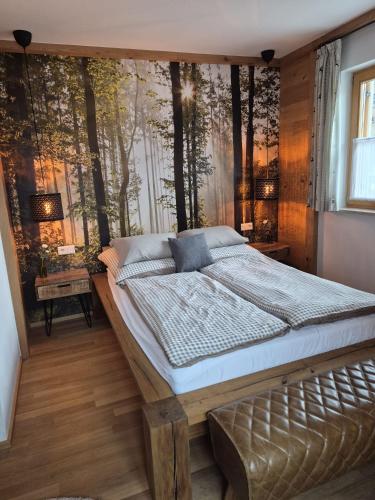 a bedroom with a large bed with trees on the wall at Ferienwohnung Ehring in Kiefersfelden