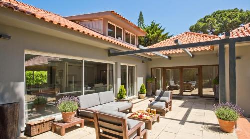 a patio with a couch and chairs on a house at The Olive Villa Cascais Vive el lujo sereno entre pinares junto al Atlántico 5 minutos de la playa andando in Cascais