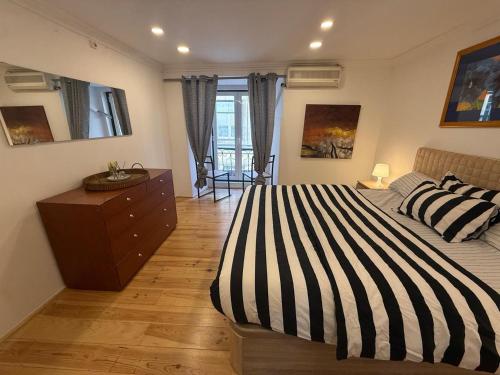 a bedroom with a black and white striped bed and a dresser at Rossio Downtown in Lisbon