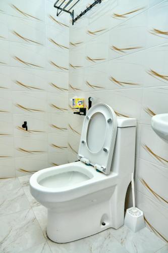 a white toilet with the seat up in a bathroom at Ngao Apartment and Suites Dodoma in Dodoma