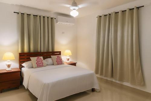 a bedroom with a bed and two lamps and curtains at Spacious Home with Private Pool in San Felipe de Puerto Plata