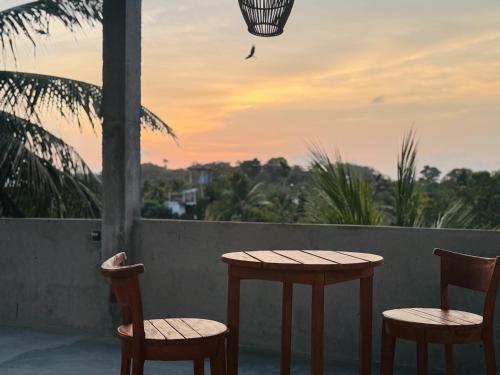 two chairs and two tables on a balcony with a sunset at SIlvas Surf Home in Weligama