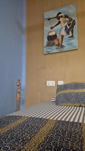 a bedroom with a bed with a painting on the wall at Emo Guesthouse in Kpandu