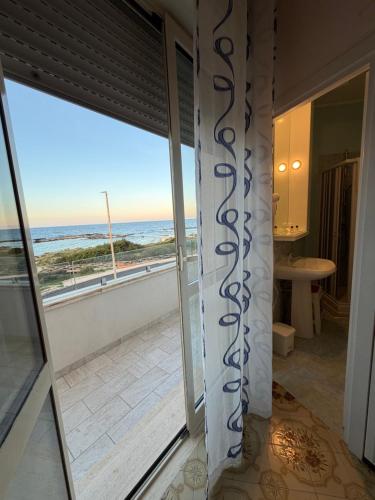 a room with a view of the ocean from a balcony at Hotel La Plancia in Otranto