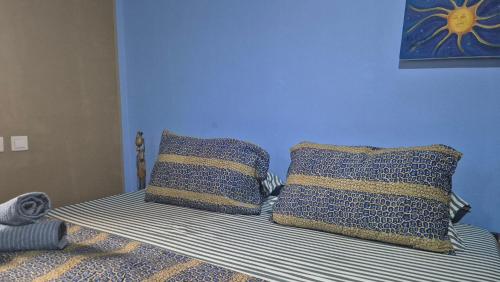 a bed with blue walls and two pillows on it at Emo Guesthouse in Kpandu