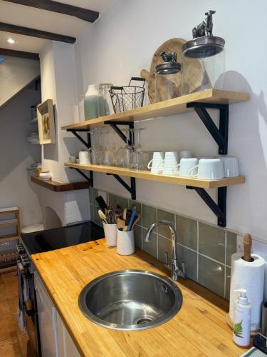 a kitchen with a sink and shelves on the wall at Norfolk Broads Bolthole in Stokesby
