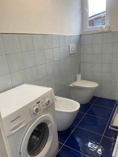 a bathroom with a washing machine and a toilet at MAGA House in Pontecagnano