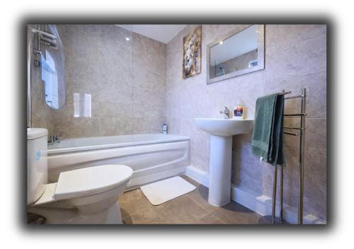 a bathroom with a toilet and a sink and a tub at Pitchside Quarters Near Anfield sleeps 7 in Liverpool