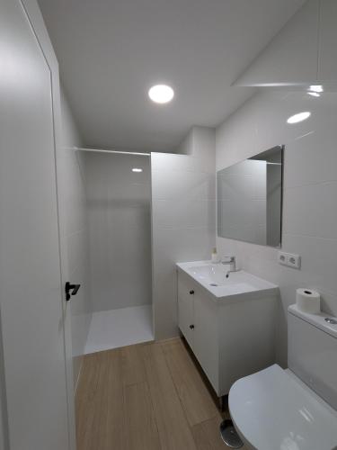a white bathroom with a sink and a mirror at Apartamento Calle Bolsa in Sanlúcar de Barrameda