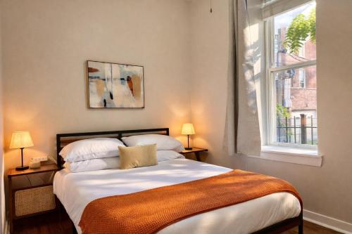 a bedroom with a bed with two lamps and a window at Flexhome West Town - Spacious 2BR Duplex - Sleeps 8 in Chicago