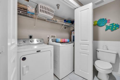 a bathroom with a toilet and a washer and dryer at Tranquillity 140 - A Wave From It All in Inlet Beach