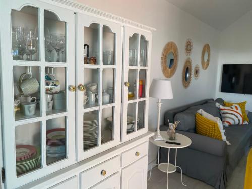 a white hutch with plates and dishes in it in a living room at Beach Flor Bungaló 42 La Gema del Sur in Maspalomas
