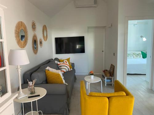 a living room with a gray couch and yellow chairs at Beach Flor Bungaló 42 La Gema del Sur in Maspalomas