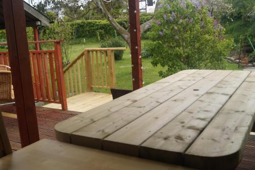 a wooden table on a deck with a view of a yard at The Narrows Guesthouse in Portaferry