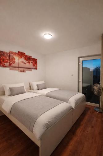 a white bedroom with two beds and a window at Basel Access Apart - Habsheim in Habsheim