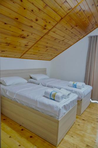two beds in a room with a wooden ceiling at Ferre Hotel Shekvetili in Natanebis Sadguri