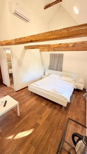 a bedroom with a white bed and a wooden floor at Apartments Choice in Velika Gorica