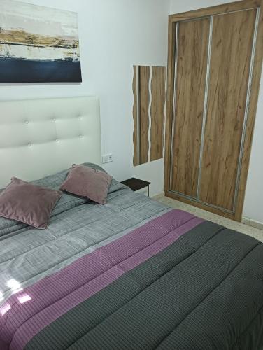 a bedroom with a bed with two pillows and a closet at Ágora House Alcalá de Guadaira 2 in Alcalá de Guadaira