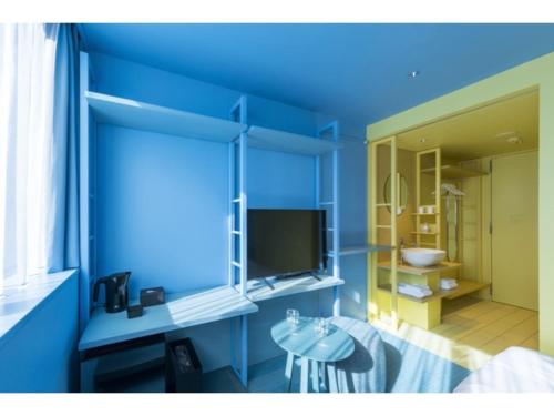 a room with a blue wall with a tv and a table at toggle hotel suidobashi - Vacation STAY 06299v in Tokyo