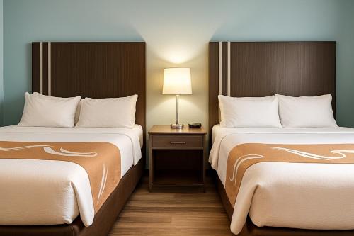 a hotel room with two beds and a table with a lamp at Village Inn & Suites in Sarnia
