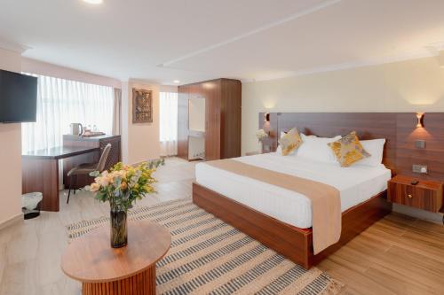 a hotel room with a large bed and a table at Karen Plains Hotel Nairobi in Nairobi