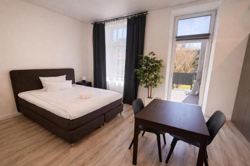 a bedroom with a bed and a table and a window at MIILOX Apartments Chemnitz Hainstrasse in Chemnitz