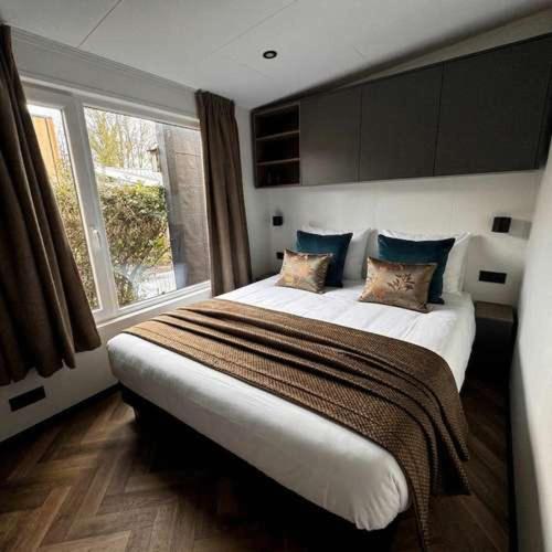 a bedroom with a large bed and a window at Luxury chalet Stay Smiley with hottub - Includes FREE pool access in Heinkensand