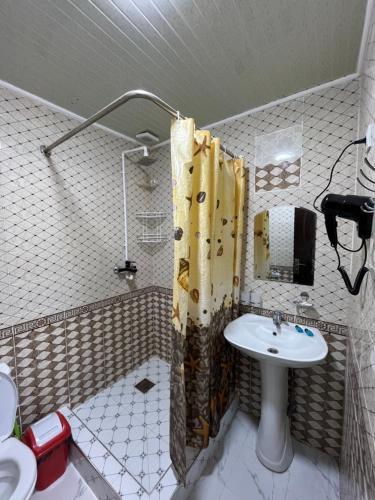 a bathroom with a sink and a shower with a shower curtain at Ichan Kala Silk Road Guest House in Khiva