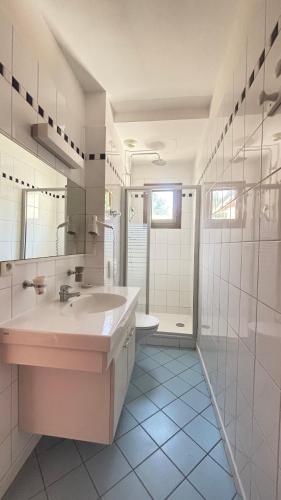 a white bathroom with a sink and a shower at Hotel La Bastide in Le Lavandou