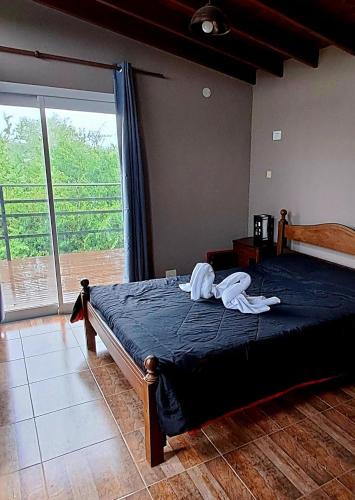 a bedroom with a bed with blue sheets and a large window at Casa de la Sierras in Cerro de Oro