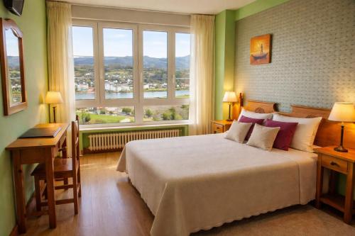 a bedroom with a large bed and a large window at Hotel Capellan in Navia
