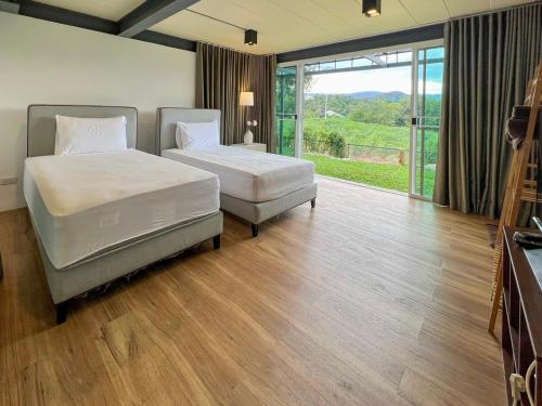 two beds in a room with a large window at Little Tree House in Mu Si