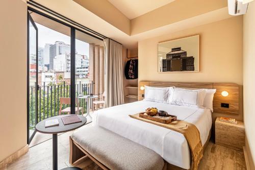 a hotel room with a bed and a balcony at Kukun Edition Marsella Juarez - Roma in Mexico City