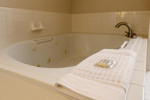 a white bath tub with a towel on it at Village Inn & Suites in Sarnia