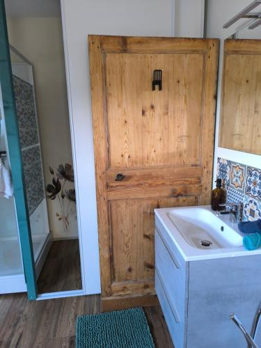a bathroom with a wooden door next to a sink at La Bruyère - B & B - in Tréban