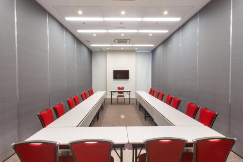 a conference room with white tables and red chairs at Ramada by Wyndham Campinas Viracopos in Campinas