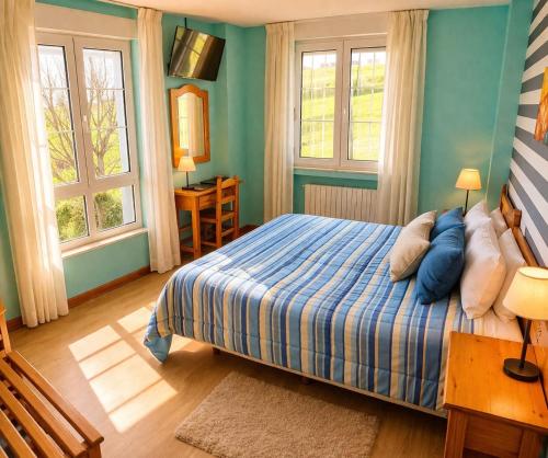 a bedroom with a bed with blue walls and windows at Hotel Capellan in Navia