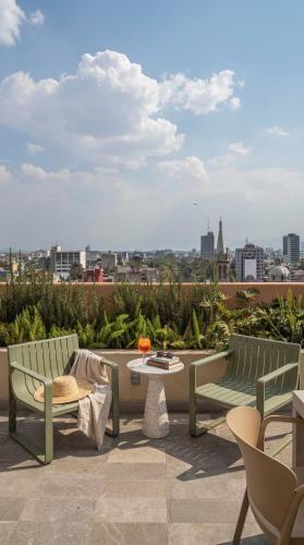 a patio with two green benches and a table at Kukun Edition Marsella Juarez - Roma in Mexico City