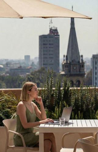 a woman sitting at a table with a laptop at Kukun Edition Marsella Juarez - Roma in Mexico City