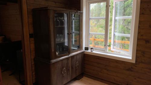 a wooden cabinet in a room with two windows at Tronstadbu- 1800s Cabin near Geirangerfjord & Slogen Hike in Hellesylt