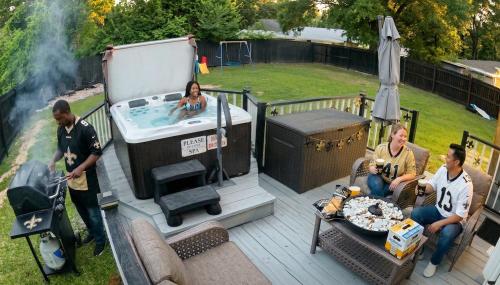 a group of people sitting on a deck with a hot tub at Tiny Home in Town-Hot Tub - Privacy Fence - Fire Pit - Kids Play Area & 15 minutes to the Bogue Chitto State Park in Franklinton